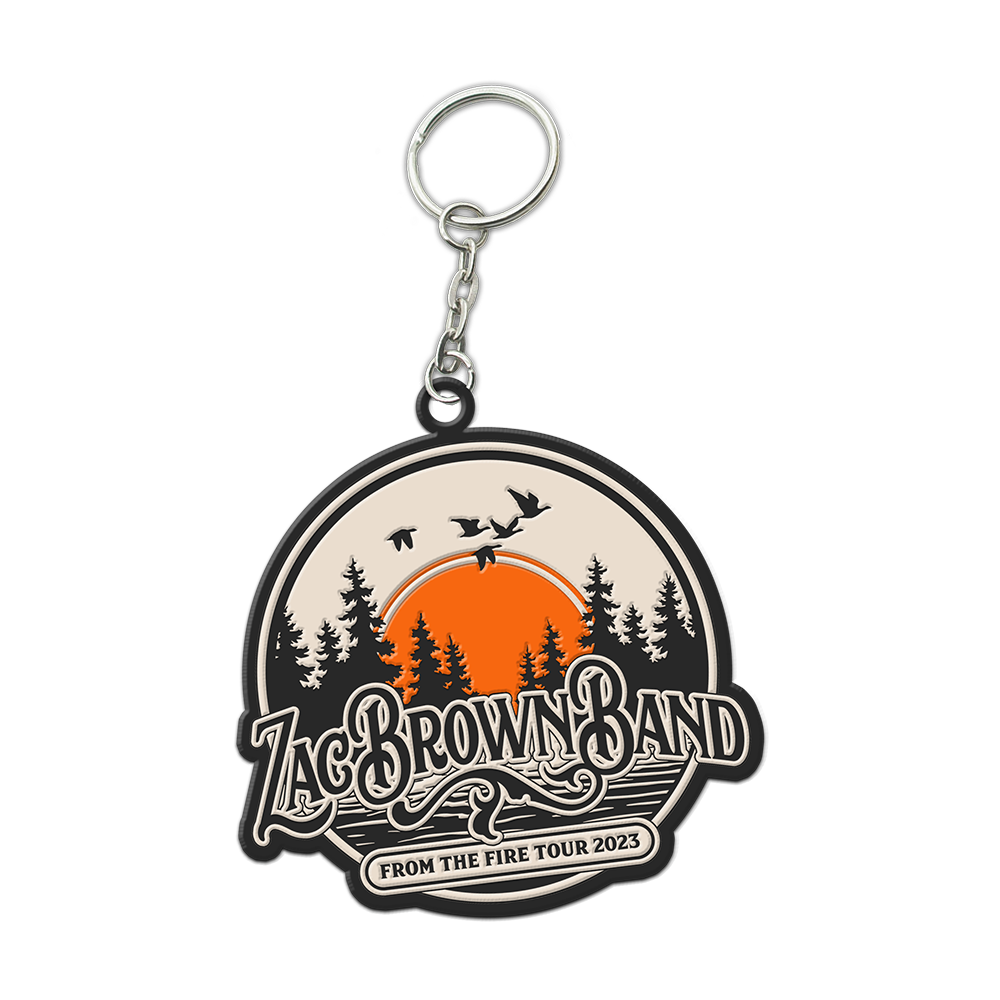 Keychain featuring a circular logo for Zac Brown Band’s ’From the Fire Tour 2023’ with a forest and sunset design.