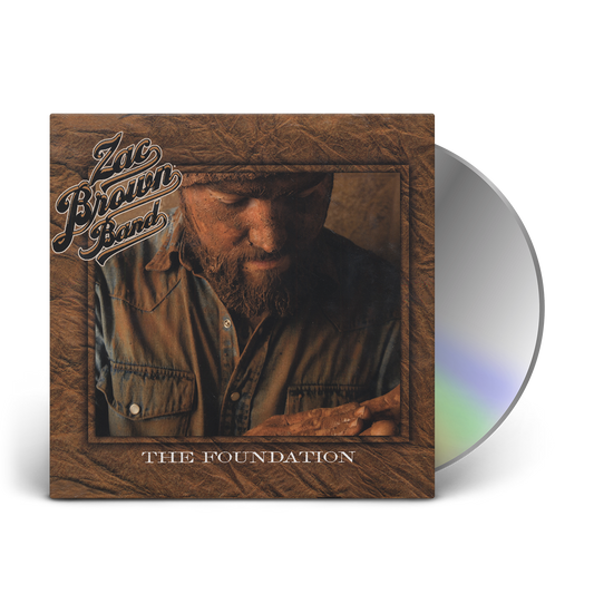 Album cover for ’The Foundation’ by Zac Brown Band featuring a CD and a sepia-toned photograph of a bearded man in a button-up shirt.
