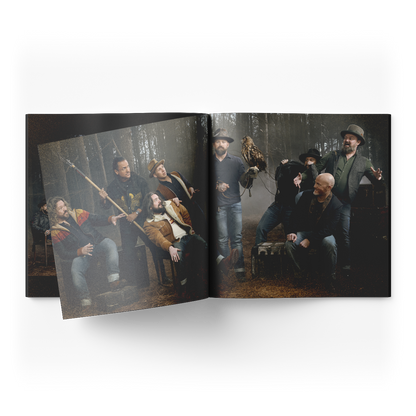 Open book displaying a dramatic group photograph of several people in a misty forest setting.