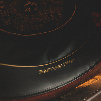 Zac Brown branded black hat with gold lettering and trim.
