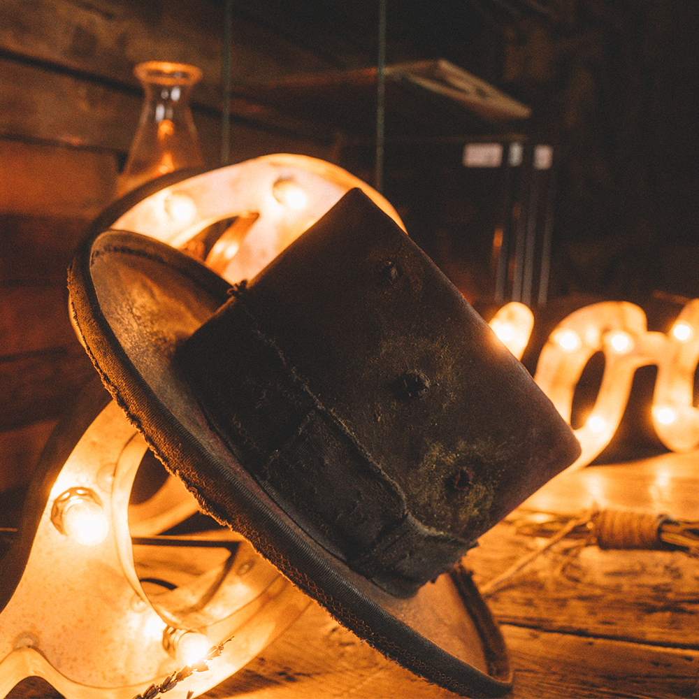 Worn, black top hat illuminated by string lights.