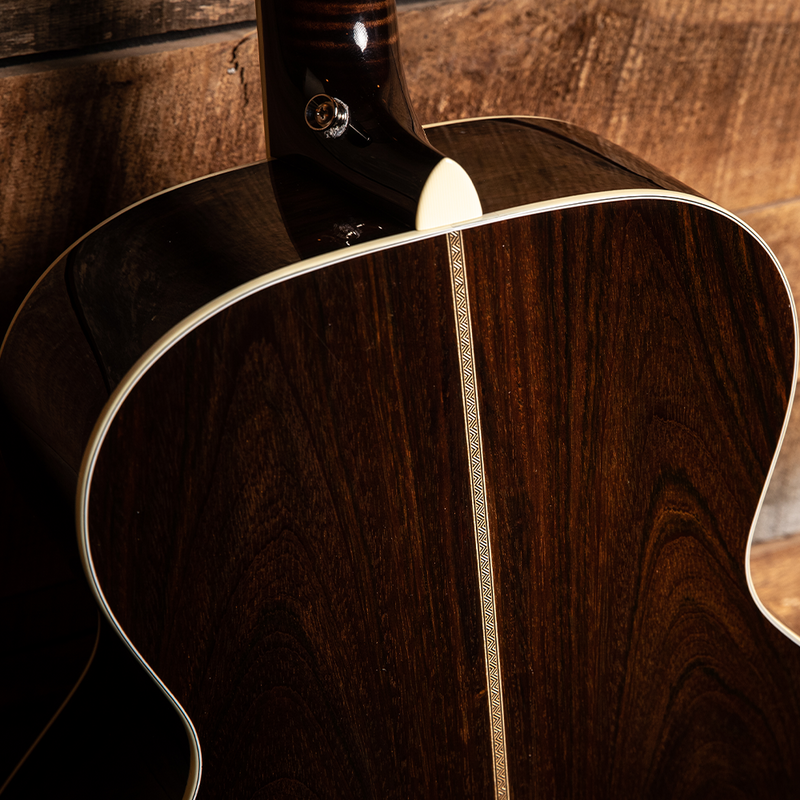 Acoustic guitar with a dark wood body and decorative inlay along the center seam.